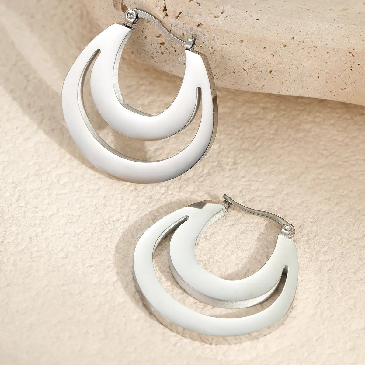 Geometric metallic French earrings with round ring elements in gold and steel finishes