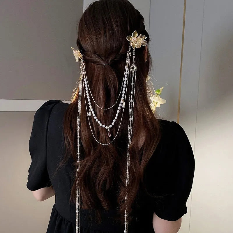 Gold women's hairpin with acrylic pearl flower, long tassels, and diamond-bead grip on a metallic pin.