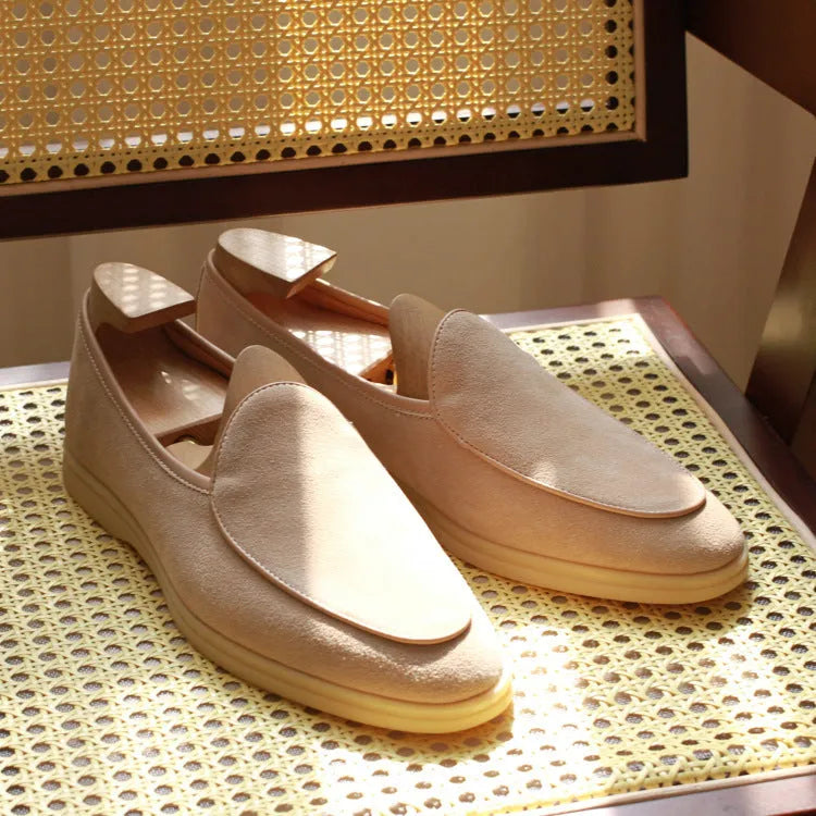 British handmade men's brown genuine leather flat loafers on a plain background.
