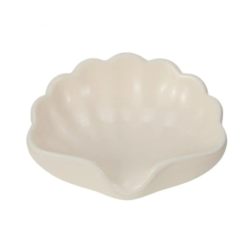 White shell-shaped plastic soap dish with drainage holes on a bathroom counter.