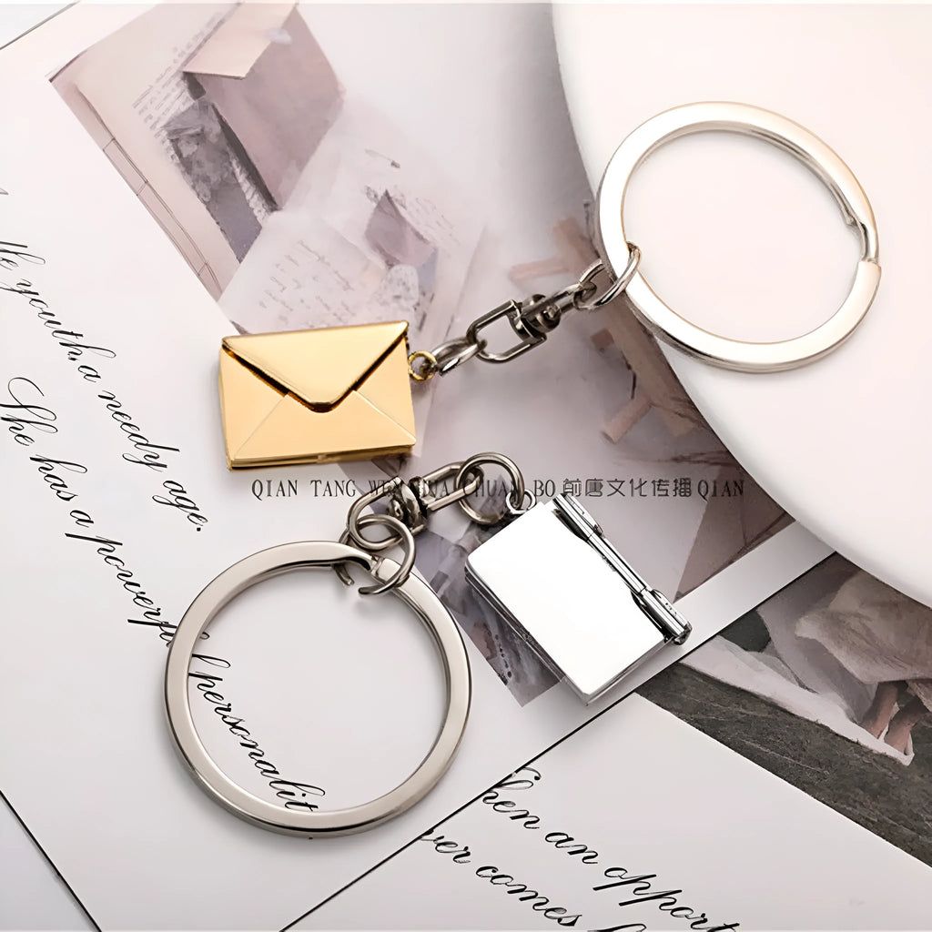 Stainless steel keychain with engraved card inside, shown in silver or gold envelope style