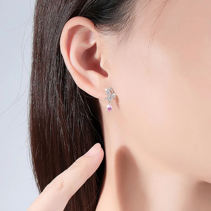 A pair of silver stud earrings featuring a butterfly design with crystal details on a white background.