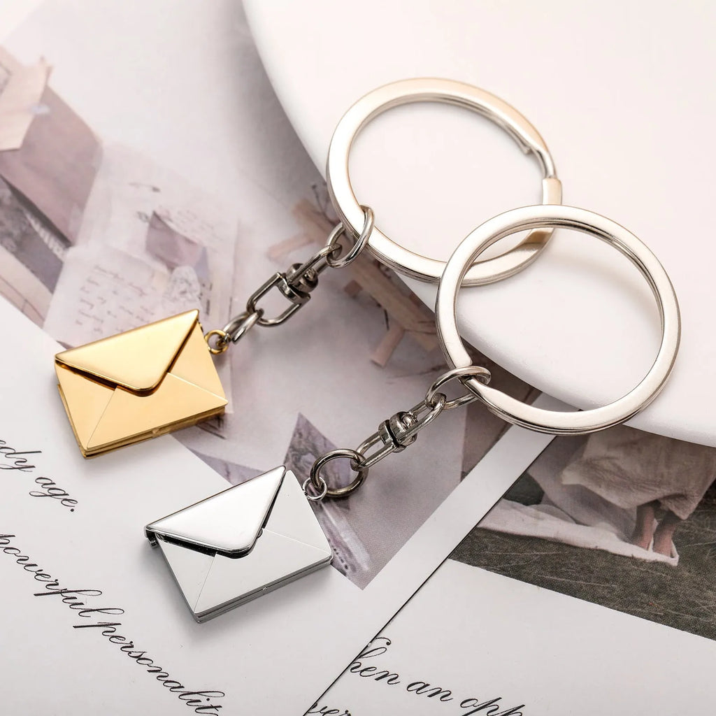 Stainless steel keychain with engraved card inside, shown in silver or gold envelope style