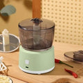 White or light green mini electric meat grinder with transparent cup on anti-slip base