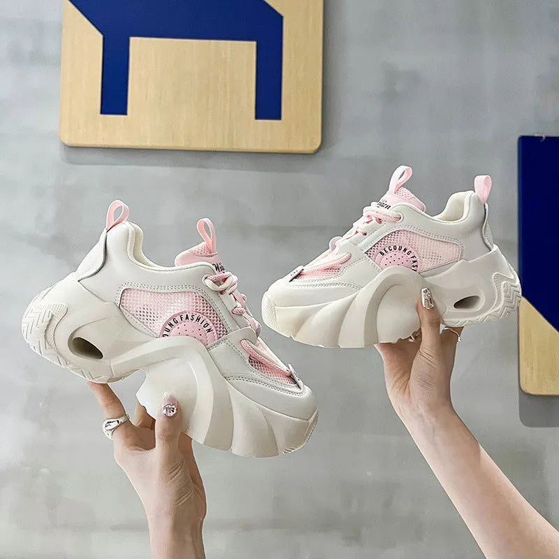 Women's pink platform sneakers with cross straps and a thick sole on a white background.
