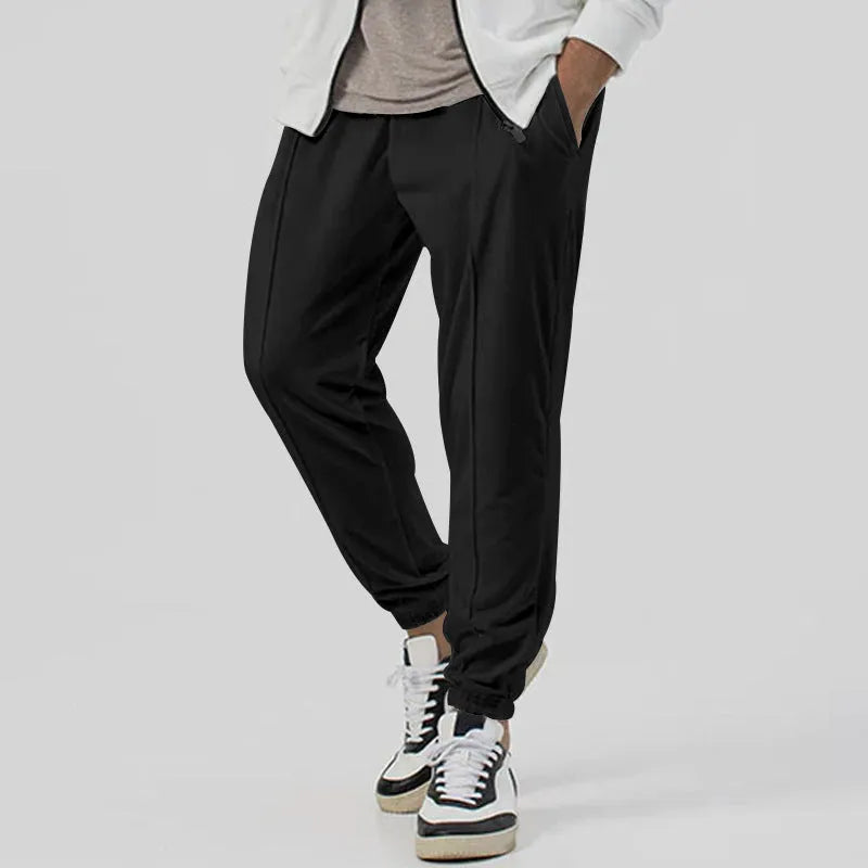 Man wearing grey loose tapered track sweatpants with a straight-leg design and elasticated waist.