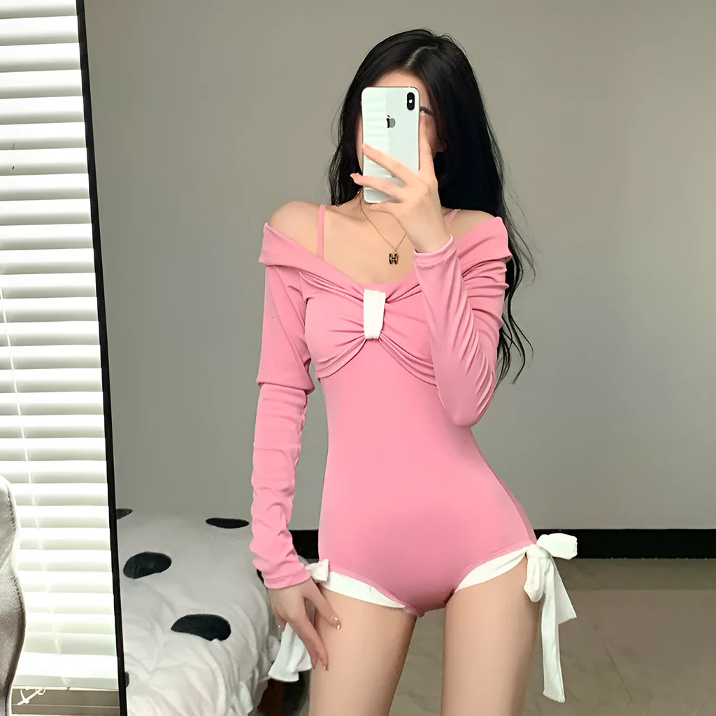 Women's pink and black long sleeve one-piece swimsuit on a hanger