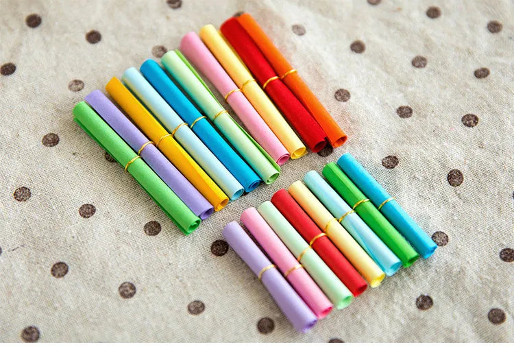 Coloured paper scrolls with metal eyelets in sizes 3x7cm, 4x7cm, 5x5cm, and 7x7cm for message writing.