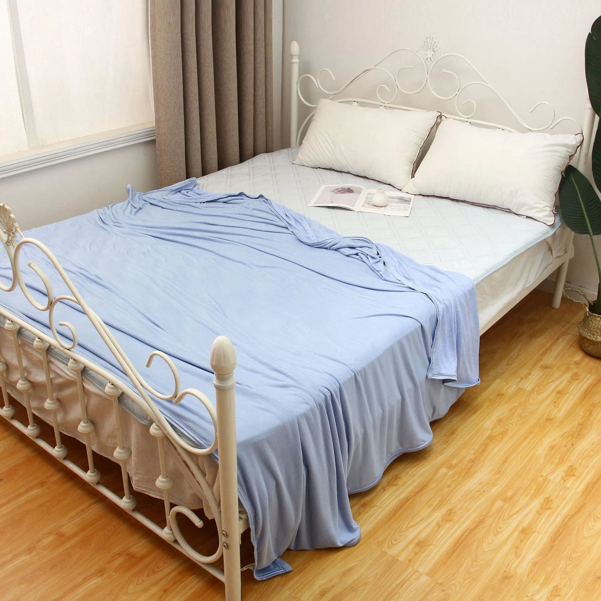 Blue cooling blanket with double-faced texture on a bed, showing its lightweight drape.