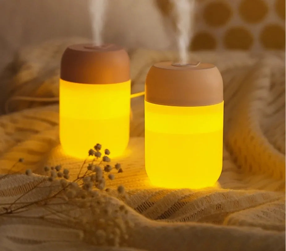 White cylindrical USB-powered mini humidifier with aromatherapy function on a wooden desk.