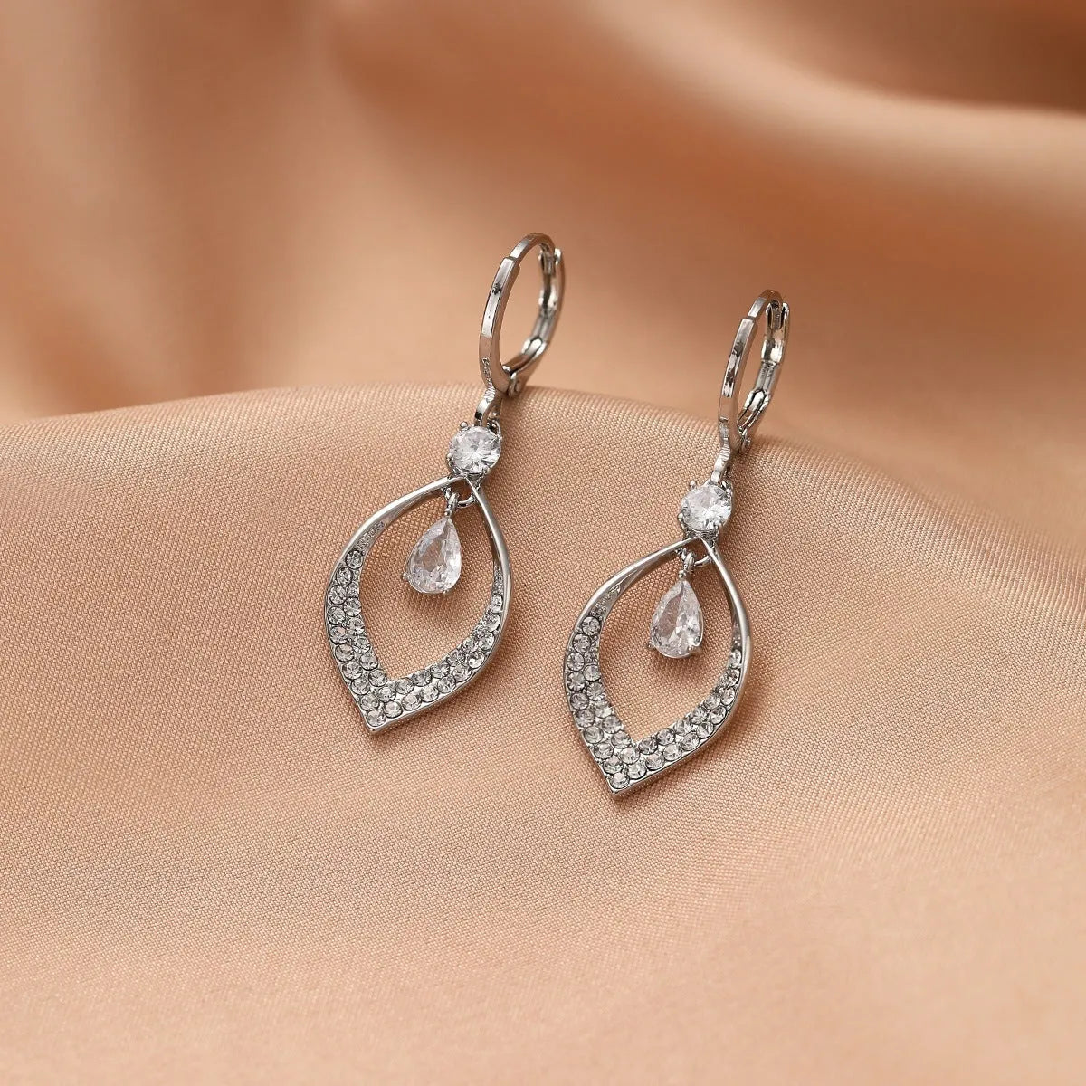 Close-up of a woman's gold-coloured water drop tassel earring with a teardrop shape and dangling details.