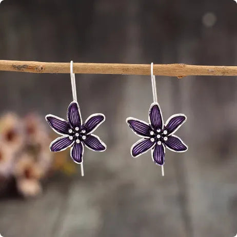 Close-up of a pair of purple flower-shaped alloy stud earrings with an electroplated finish.