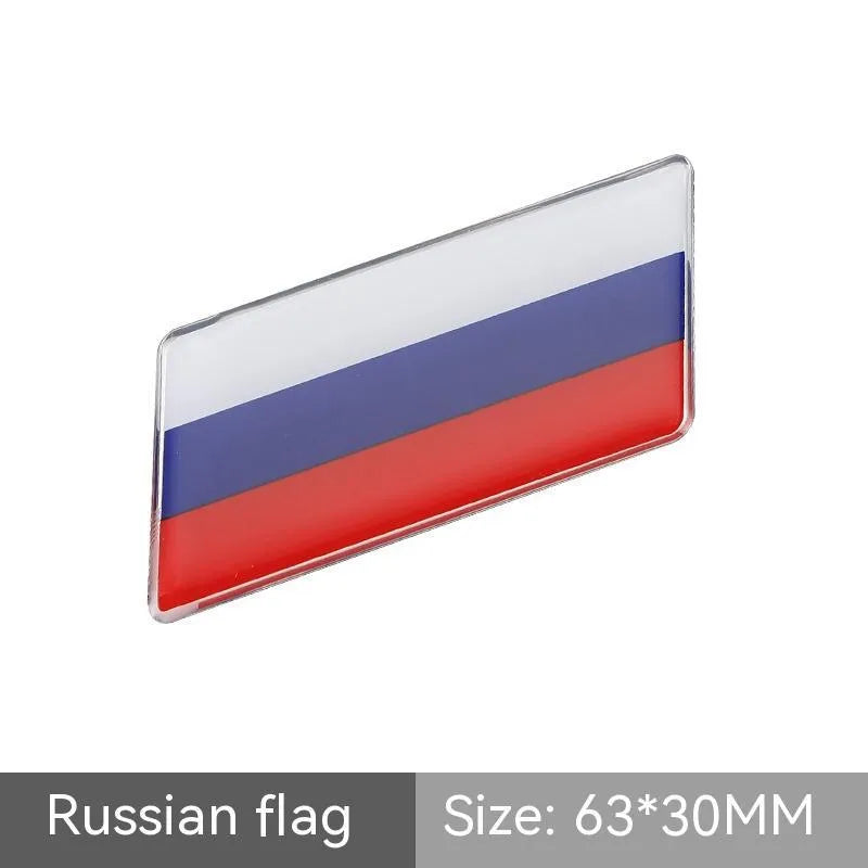 Aluminium national flag car sticker in a parallelogram shape measuring 6.3 by 3 centimetres.