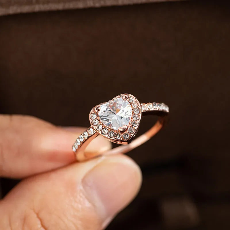 Women's heart-shaped crystal wedding ring in rose gold or silver on a white background.