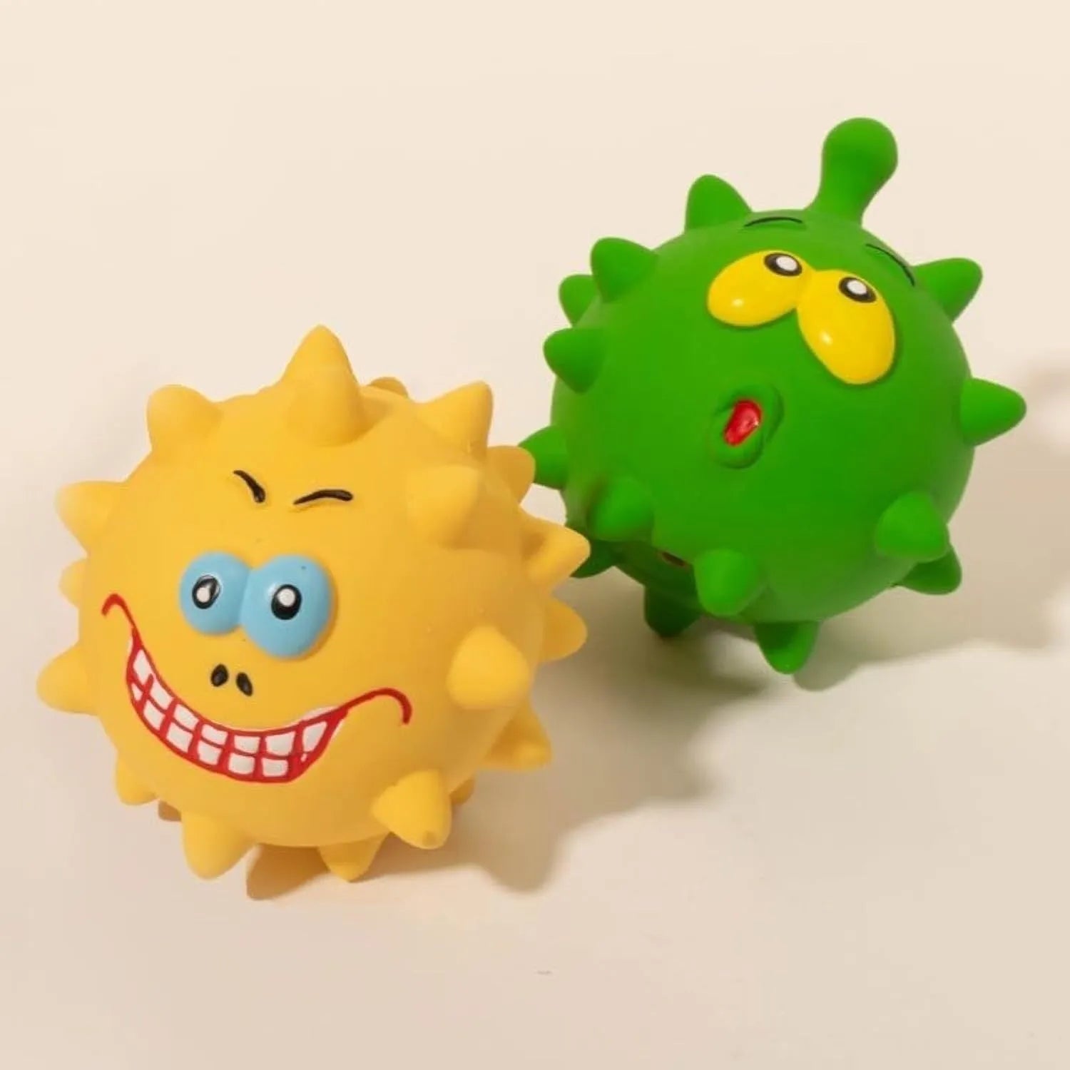 Set of four colourful squeaky latex dog balls with cute faces, shown next to a dog.