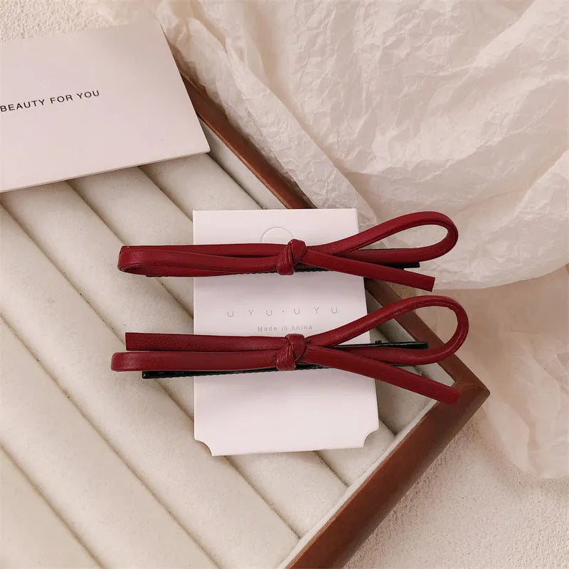 Wine red leather bow hair barrette on white background showing handmade construction