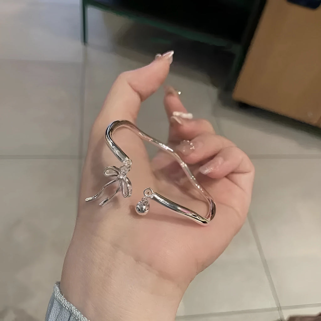 Silver adjustable bracelet with bow charm and opening bell clasp