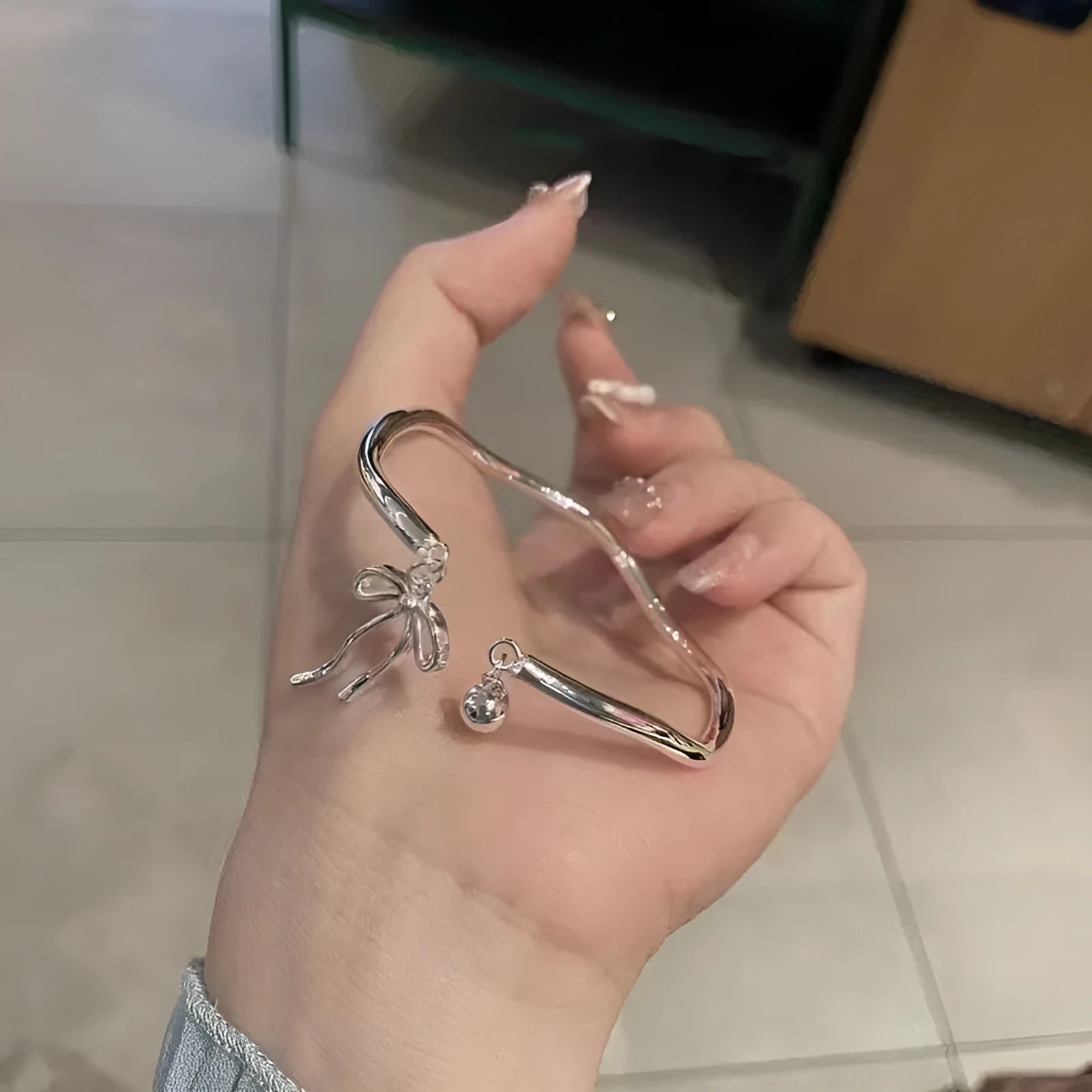 Silver adjustable bracelet with bow charm and opening bell clasp
