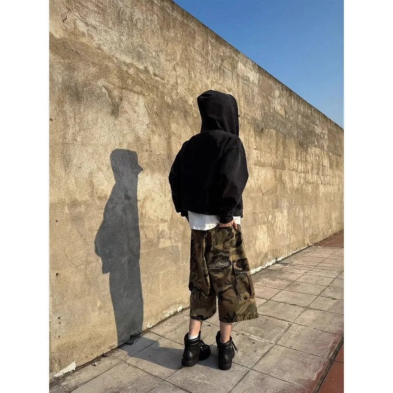 Man wearing loose fit camouflage print cropped jeans with ripped knees and patchwork details.