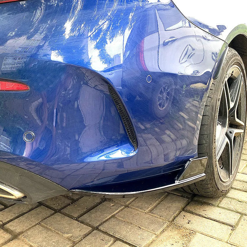 Pair of car rear bumper corner protectors in carbon fibre pattern on a vehicle rear corner