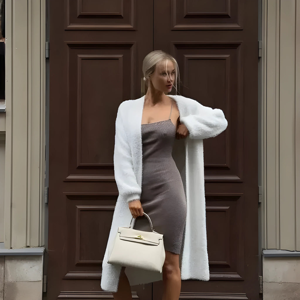 White loose-fit knitted cardigan jacket with long sleeves on a hanger.