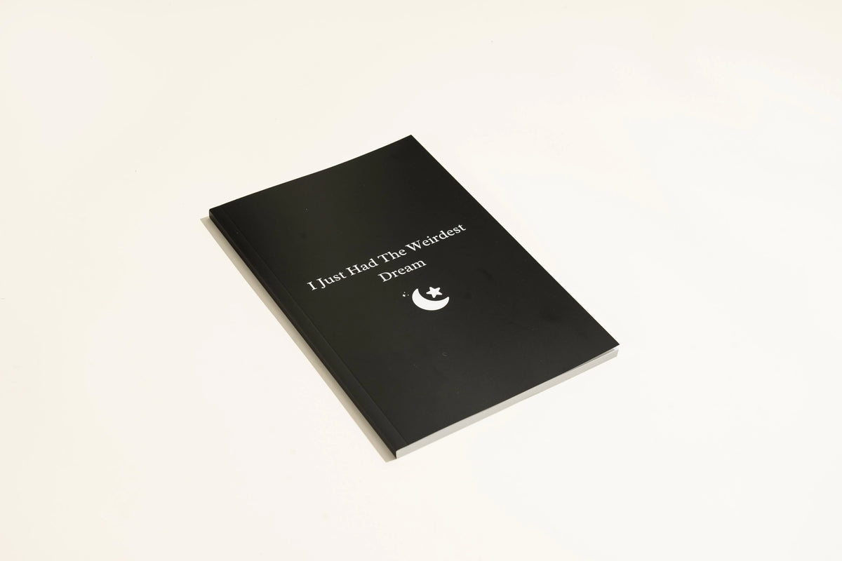 Black cover Dream Journal notebook with Business Simplicity design, open to show dot grid interior pages.