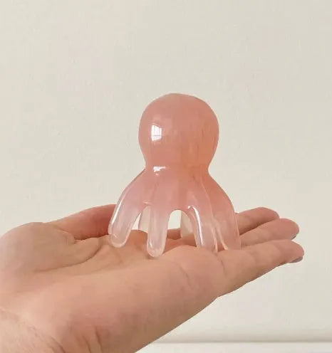 Pink octopus-shaped facial massage comb made from natural resin with storage bag