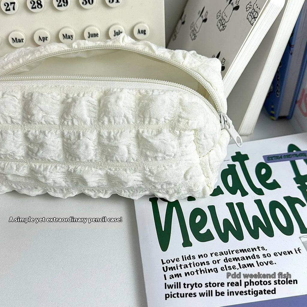 Beige and black soft fabric pencil case with a cream puff design and zip closure.