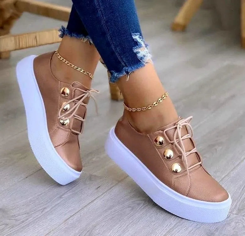 Women's white lace-up flats sneakers with decorative rivets on the artificial leather upper.
