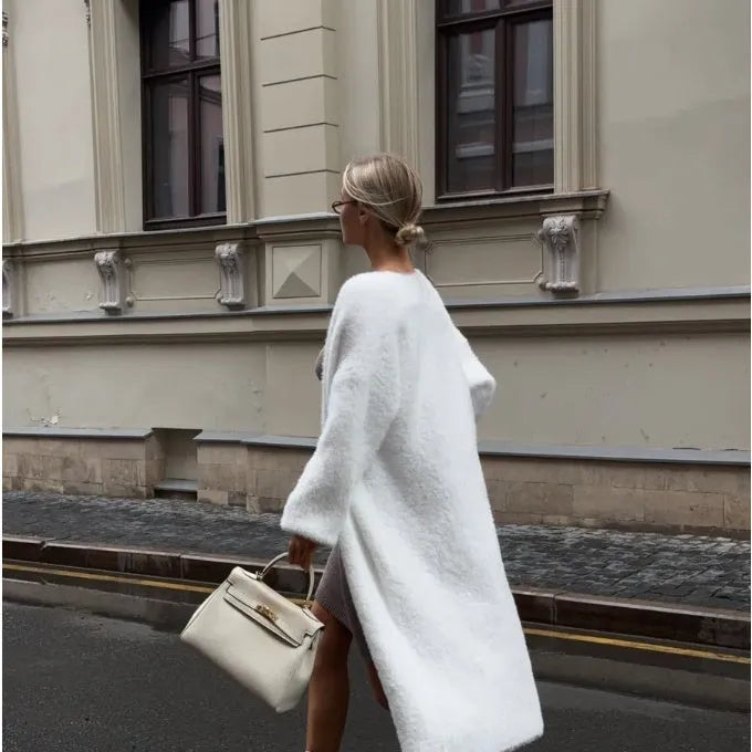 White loose-fit knitted cardigan jacket with long sleeves on a hanger.