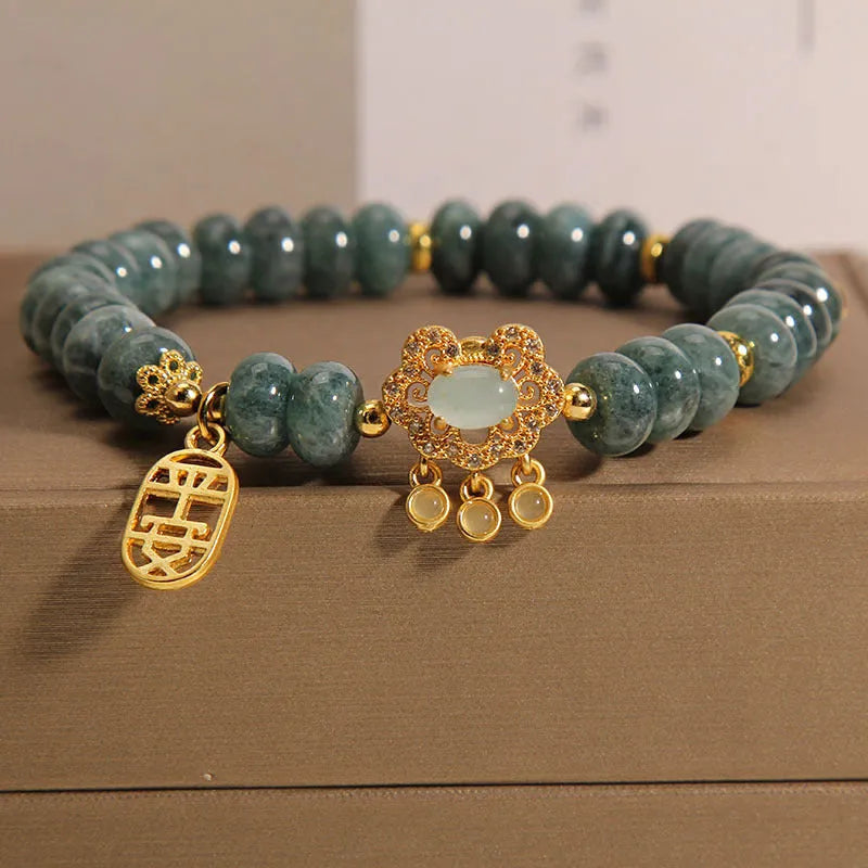 Close-up of a women's bracelet with green emerald jade abacus beads and a silver-toned alloy safety lock clasp.