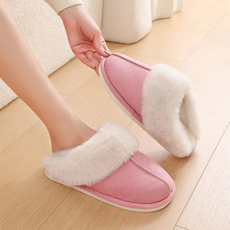 Women's plush winter slippers in pink with a round toe, flat heel, and decorative stitching.