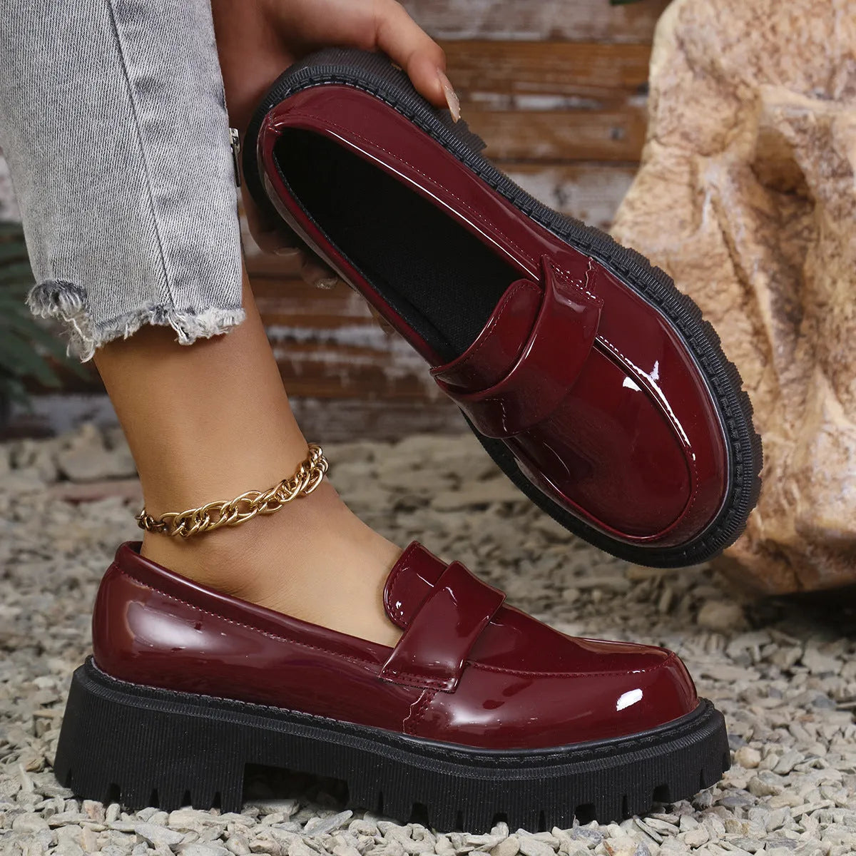 Women's black slip-on loafers with a chunky platform heel on a wooden floor