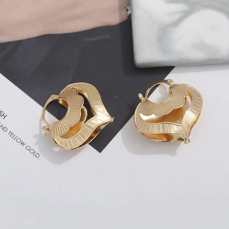 Gold electroplated copper heart-shaped hollow stud earrings with lace-inspired openwork design and geometric round elements