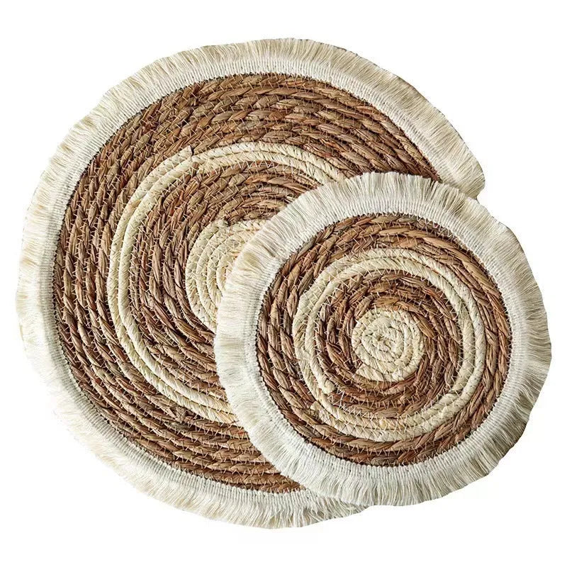 Round natural papyrus straw placemat with tassel detailing on a table.