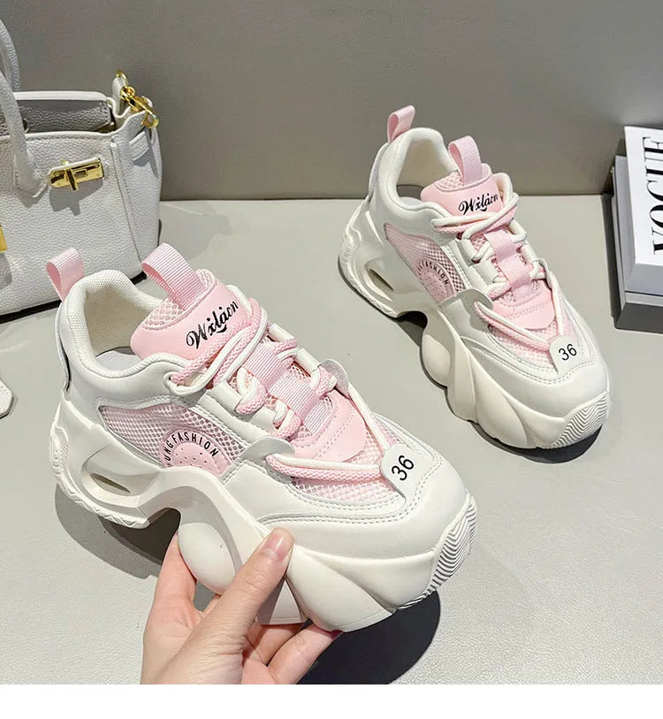 Women's pink platform sneakers with cross straps and a thick sole on a white background.
