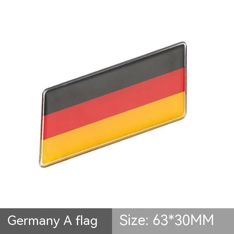 Aluminium national flag car sticker in a parallelogram shape measuring 6.3 by 3 centimetres.