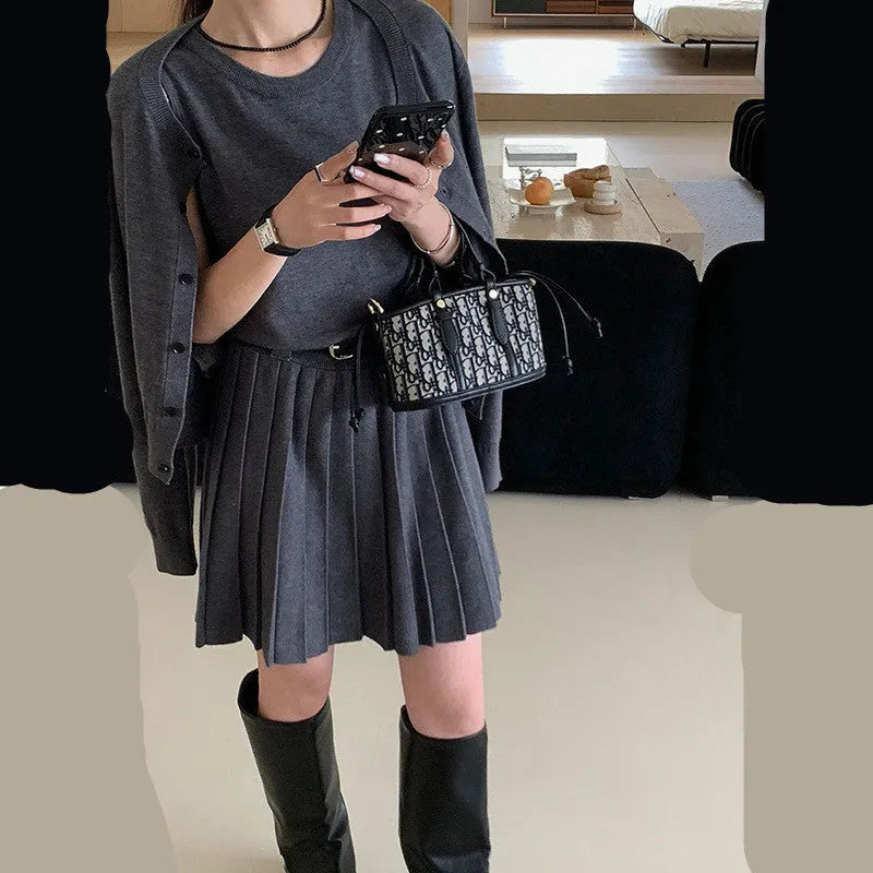 Women's black knitted two-piece set showing vest skirt with belt and long-sleeved cardigan with 3D pattern