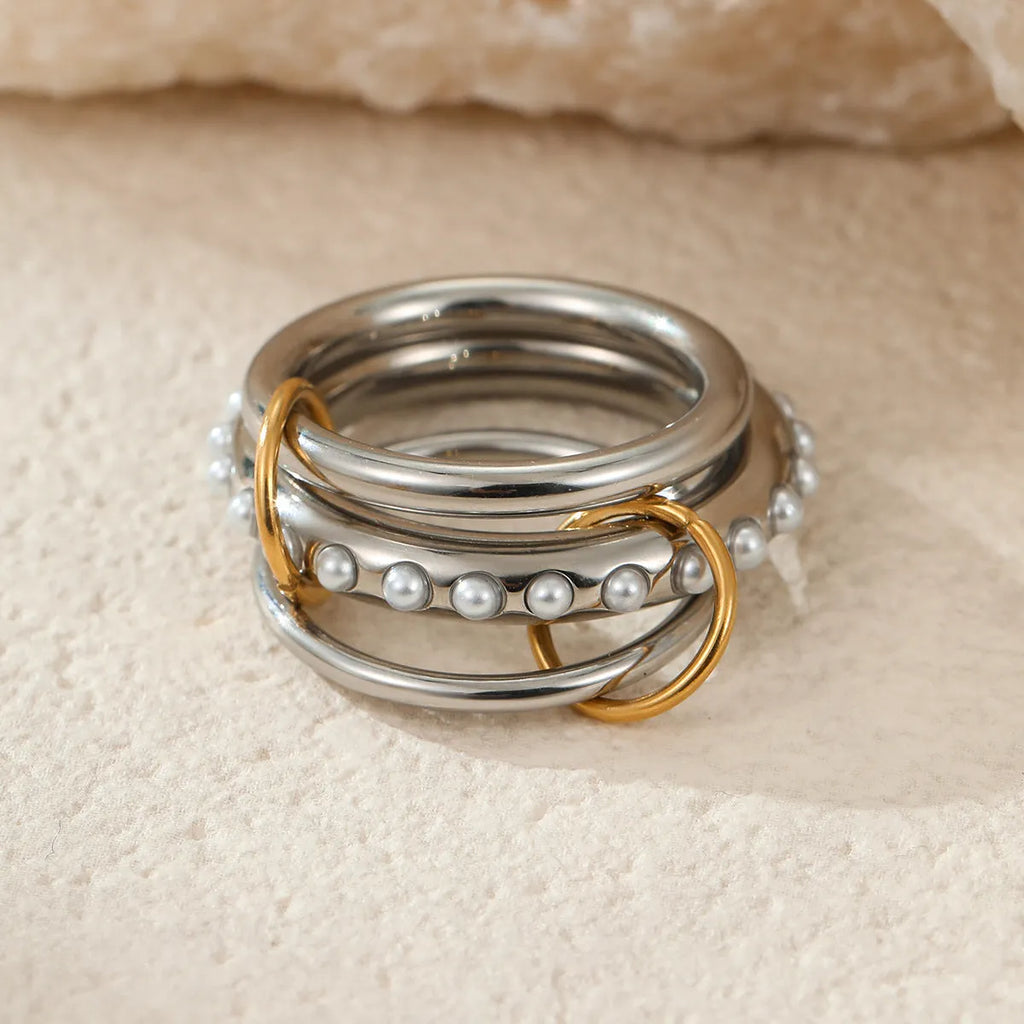 Stacked gold plated stainless steel rings with exaggerated designs on woman's hand