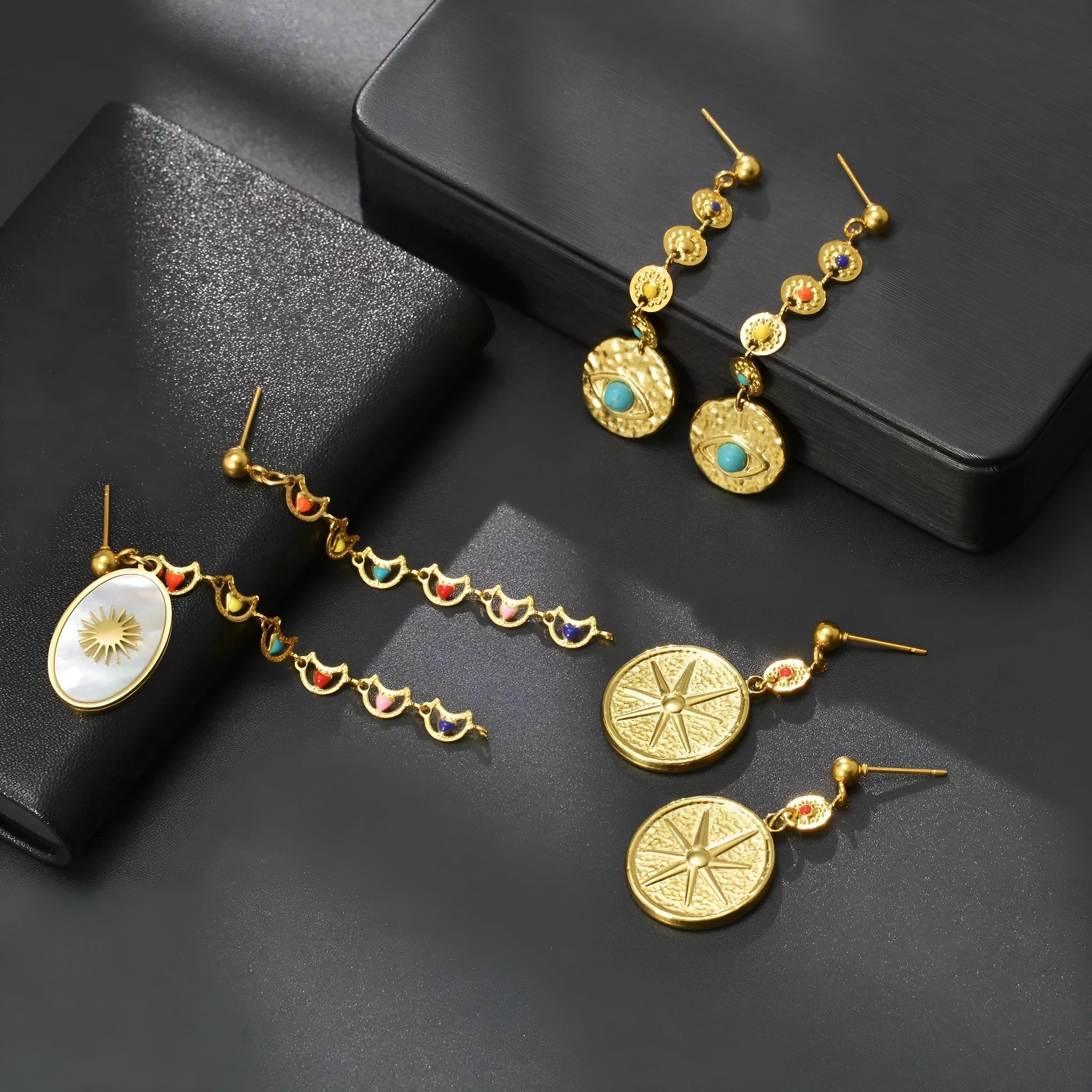 Stainless steel geometric drop earrings showing three designs: eight awn star, eye shape, and shell sun pattern