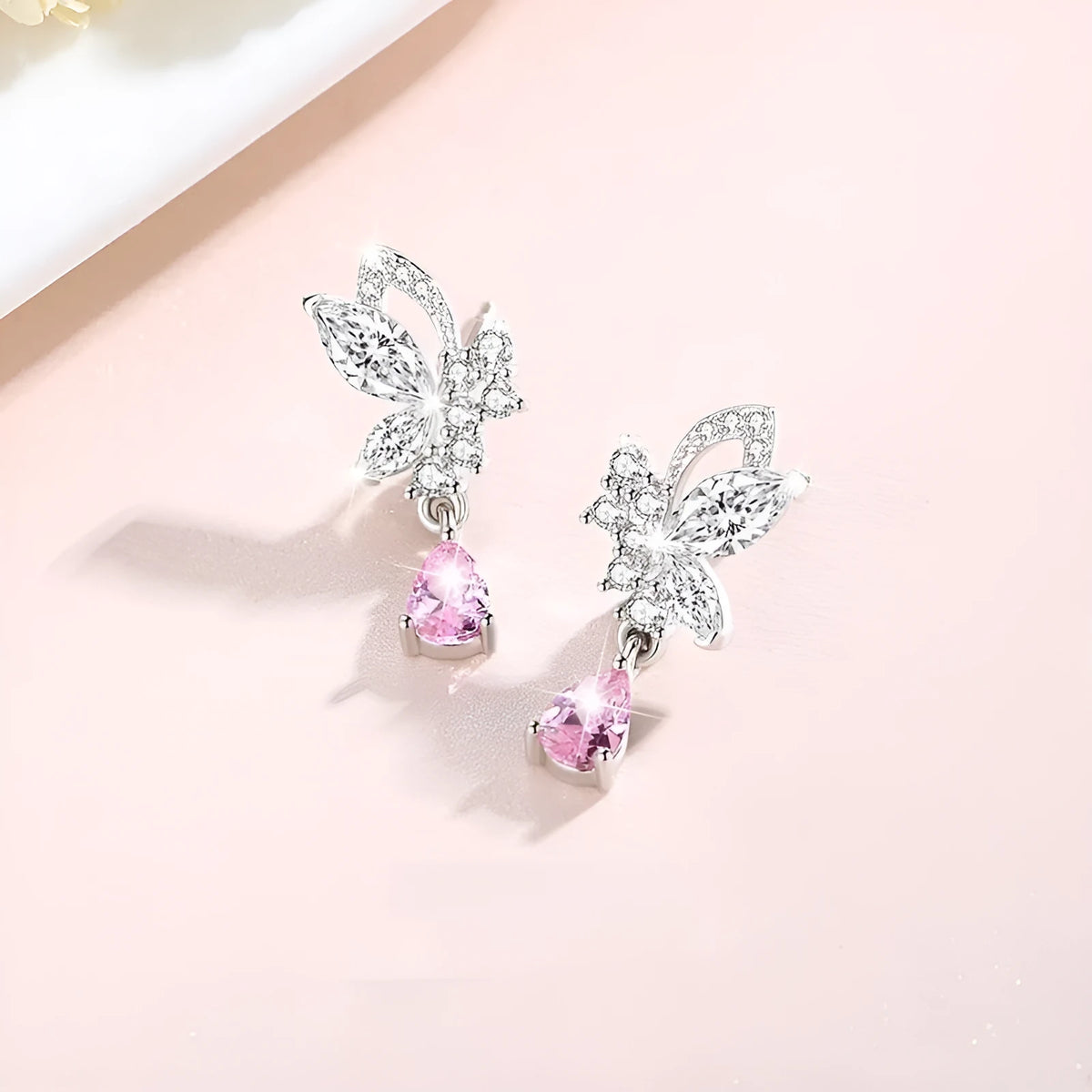 A pair of silver stud earrings featuring a butterfly design with crystal details on a white background.