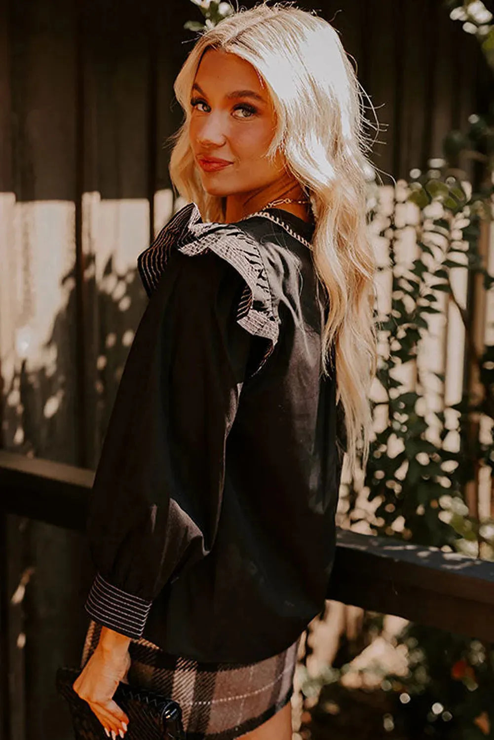 Black women's V-neck blouse with long ruffle sleeves and contrast colour stitching.