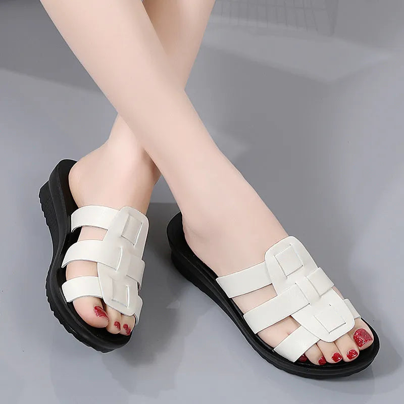 Beige women's flat-bottom slippers with waxed leather upper and soft PU sole on a wooden floor.
