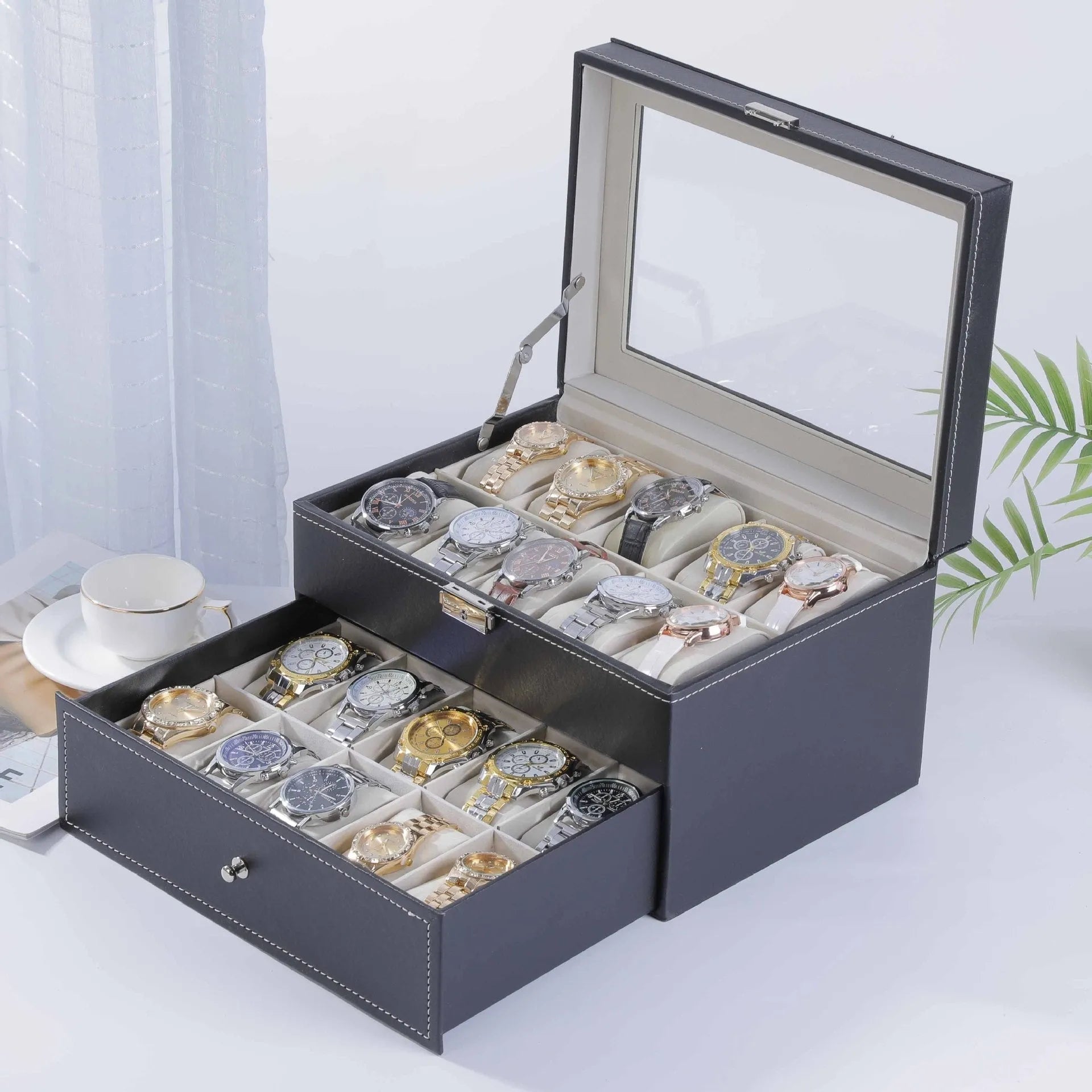 Grey leather watch storage box with transparent lid showing multiple watch slots inside.