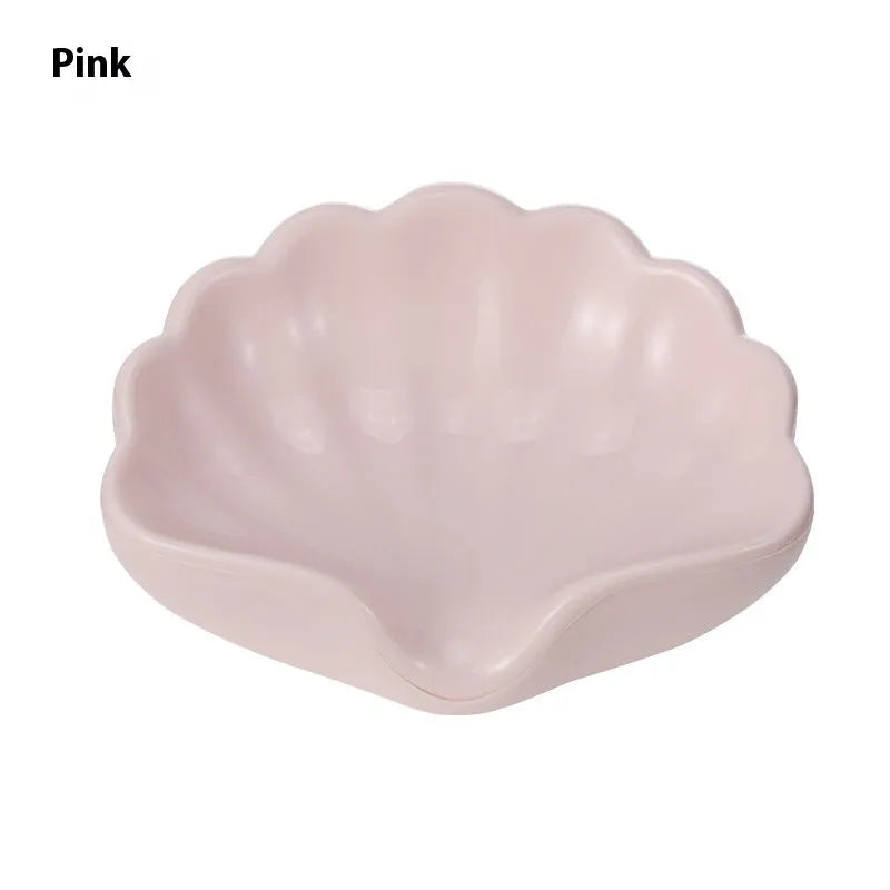 White shell-shaped plastic soap dish with drainage holes on a bathroom counter.