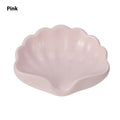 White shell-shaped plastic soap dish with drainage holes on a bathroom counter.