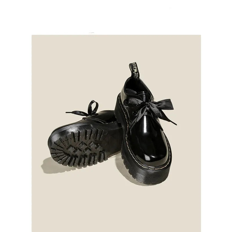 Black thick soled women's lace-up shoes with ribbon and cross strap details on a white background.