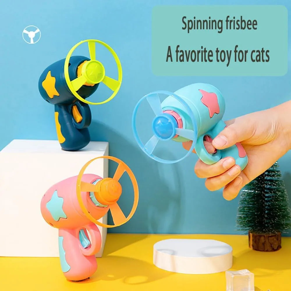 Blue plastic interactive cat toy gun with a mounted pink Frisbee on a table.