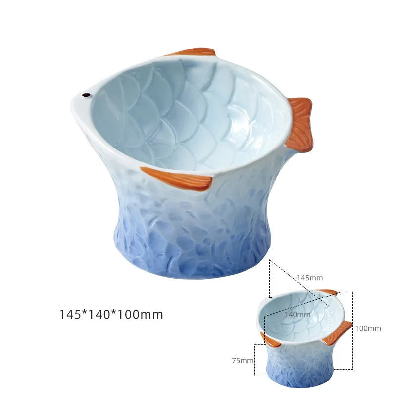 Four coloured fish-shaped ceramic pet bowls with a tilted, elevated design on a plain surface.