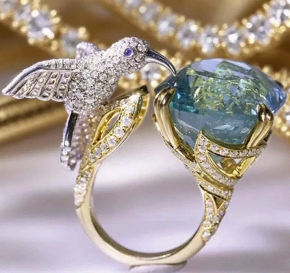 Ocean blue topaz hummingbird open ring with real gold coloured brass finish and adjustable opening.